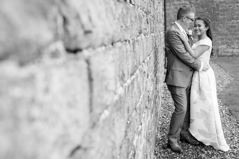 Bride and Groom standing against wall