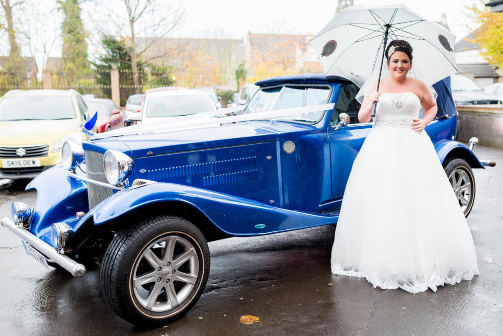 Bride standing next to stunning wedding car