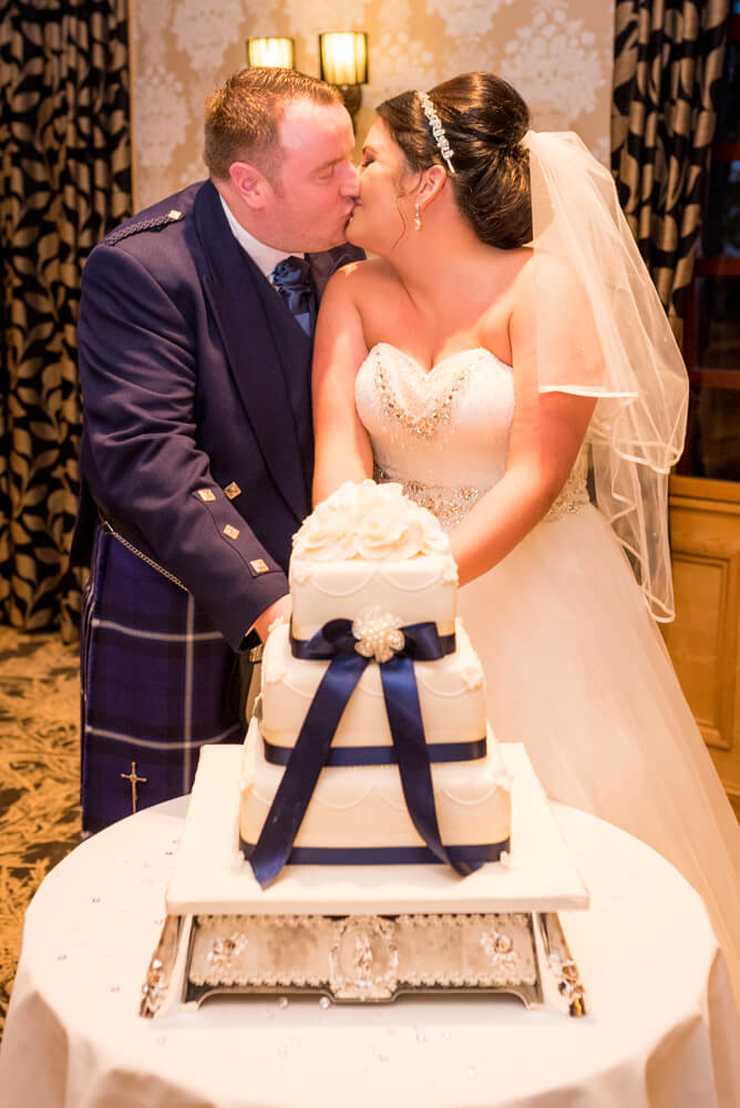 Bride and groom cutting cake and kissing at The Parkville Hotel
