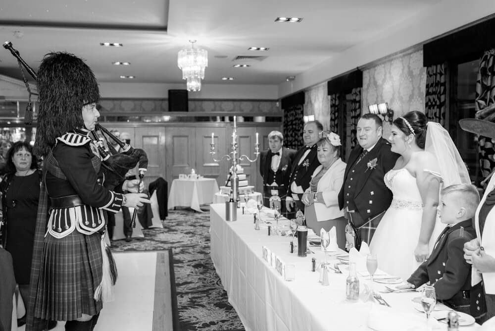 Piper playing his bagpipes in front of the top table
